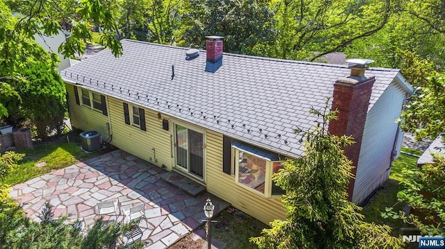 rear view of house with a chimney, a patio area, and central AC unit