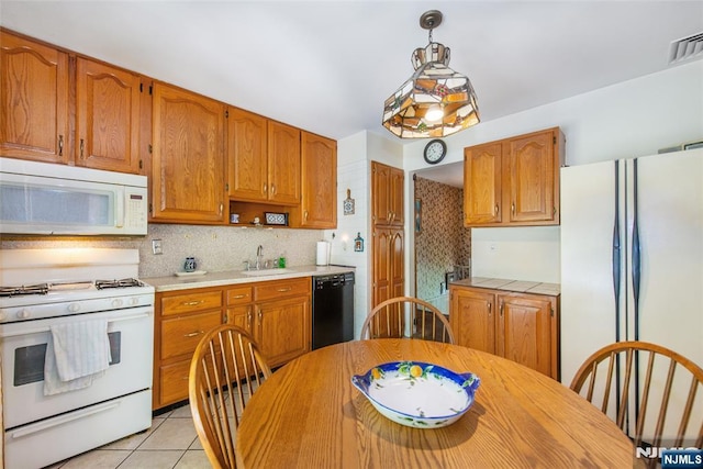kitchen featuring white appliances, light tile patterned flooring, a sink, backsplash, and brown cabinets