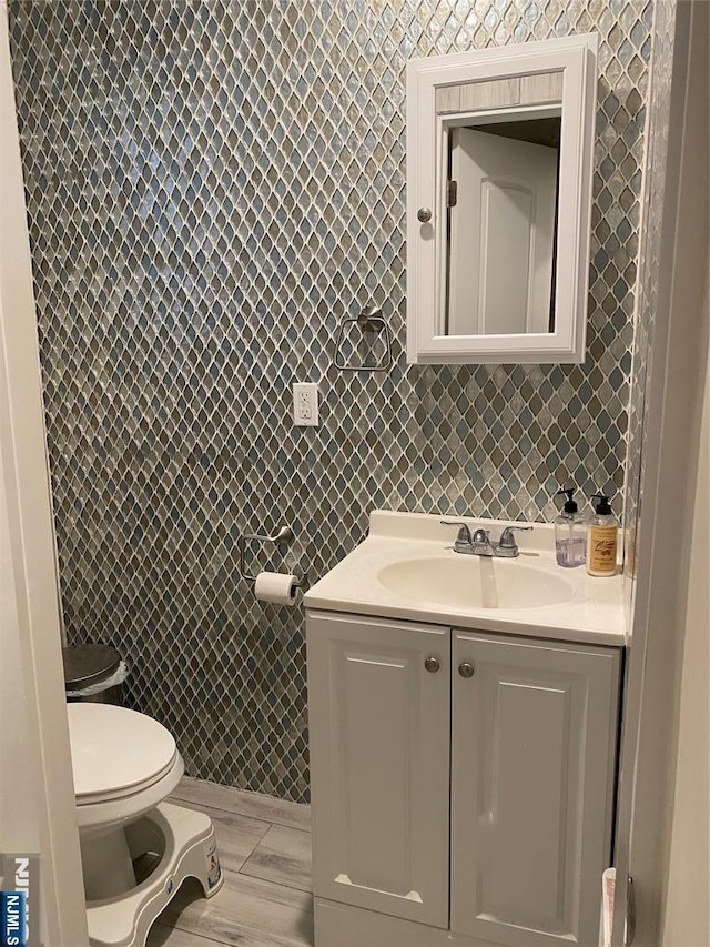 half bathroom with toilet, tile walls, and vanity