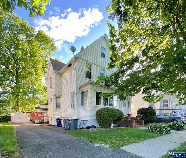 view of front of home featuring a storage unit, an outdoor structure, and a front lawn