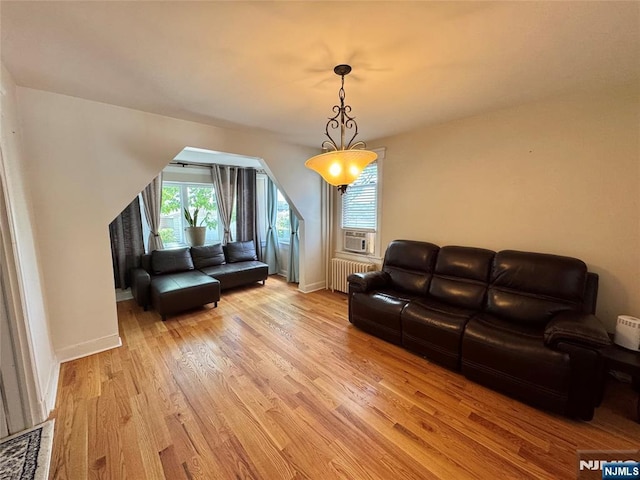 living room with light wood-style floors, radiator heating unit, baseboards, and cooling unit