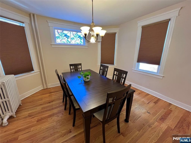 dining space featuring radiator, a chandelier, light wood finished floors, and baseboards