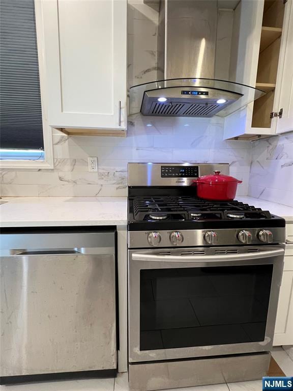 kitchen featuring appliances with stainless steel finishes, island exhaust hood, white cabinets, and backsplash