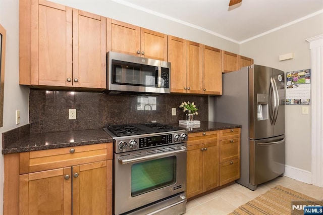 kitchen with stainless steel appliances, light tile patterned flooring, dark stone countertops, backsplash, and ornamental molding