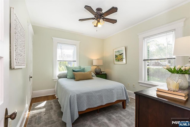 bedroom with baseboards, ceiling fan, wood finished floors, and crown molding