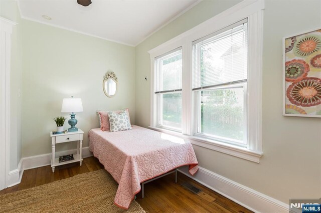 bedroom featuring wood finished floors, ornamental molding, and baseboards