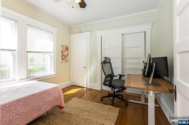 bedroom with wood finished floors, ornamental molding, baseboards, a closet, and an office area