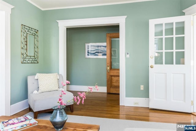living area featuring wood finished floors, ornamental molding, and baseboards