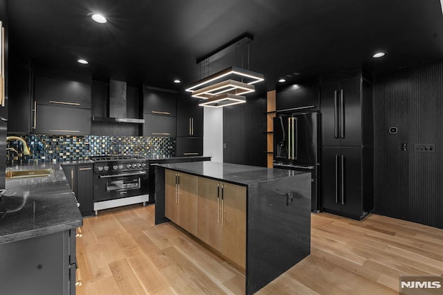 kitchen featuring black appliances, wall chimney exhaust hood, a sink, and dark cabinets