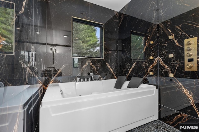 full bathroom featuring a bath, tile walls, and marble tiled flooring