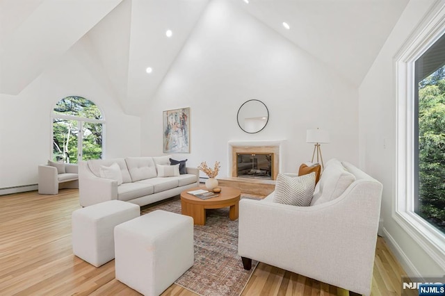 living area featuring healthy amount of natural light, light wood finished floors, recessed lighting, high vaulted ceiling, and baseboards