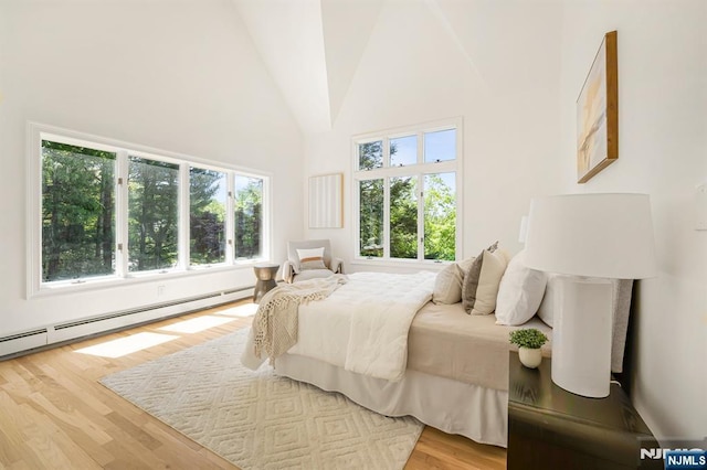 bedroom featuring a baseboard radiator, wood finished floors, multiple windows, and high vaulted ceiling