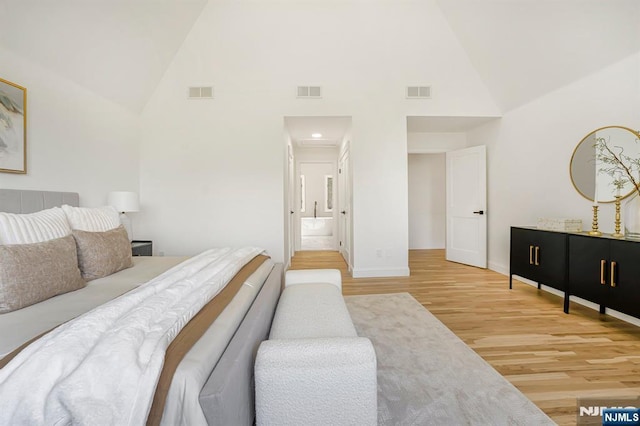 bedroom featuring high vaulted ceiling, wood finished floors, and baseboards