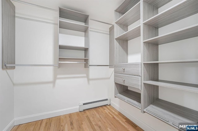 walk in closet featuring a baseboard heating unit and light wood finished floors