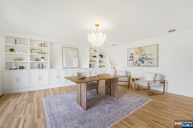 office area with light wood-style flooring, a chandelier, and built in shelves