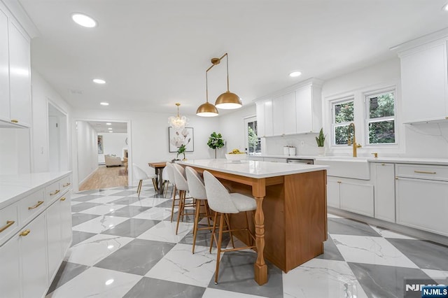 kitchen with a sink, recessed lighting, white cabinetry, a kitchen island, and pendant lighting