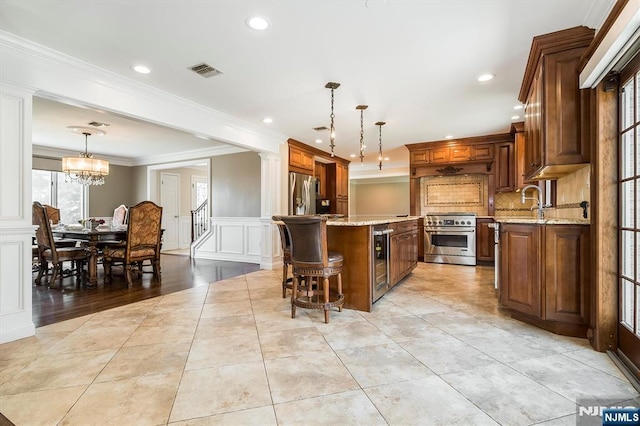 kitchen featuring stainless steel appliances, beverage cooler, a decorative wall, a kitchen island, and ornamental molding