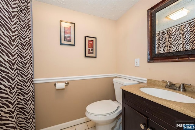 bathroom with toilet, tile patterned flooring, vanity, a textured ceiling, and baseboards