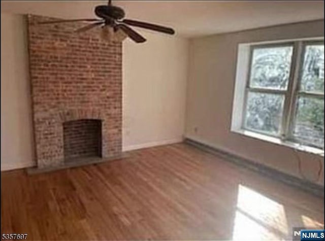 unfurnished living room featuring ceiling fan, wood finished floors, a fireplace, and baseboards