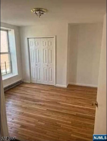 unfurnished bedroom with baseboards, wood finished floors, and a closet