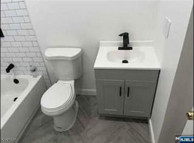 bathroom featuring toilet, vanity, and baseboards