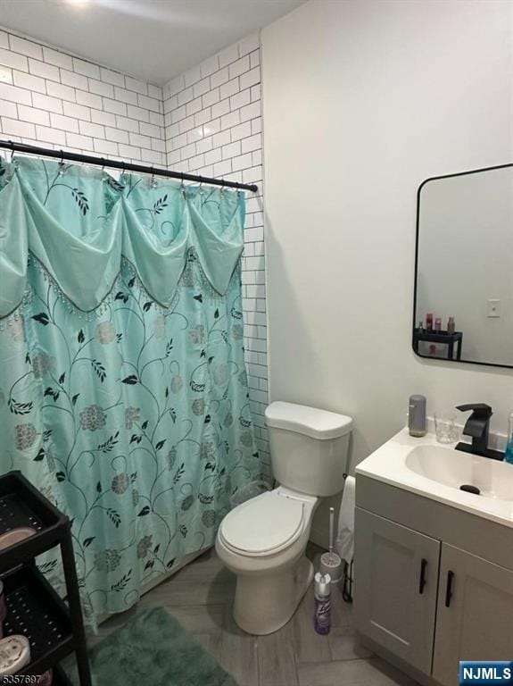 full bath featuring toilet, vanity, and a shower with curtain