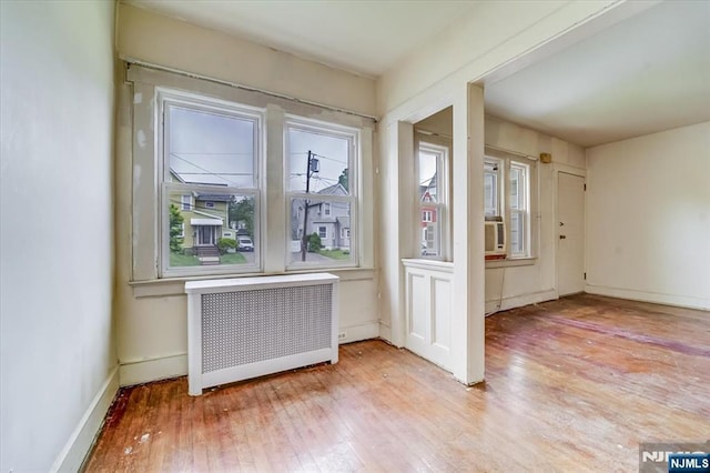 spare room with radiator, hardwood / wood-style floors, and baseboards