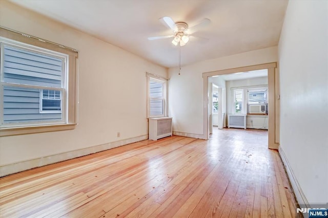 spare room with ceiling fan, radiator, wood-type flooring, baseboards, and cooling unit