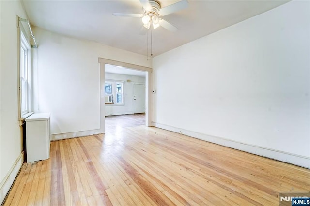 spare room with light wood finished floors, ceiling fan, a baseboard heating unit, and baseboards