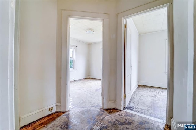 corridor with ornamental molding and baseboards