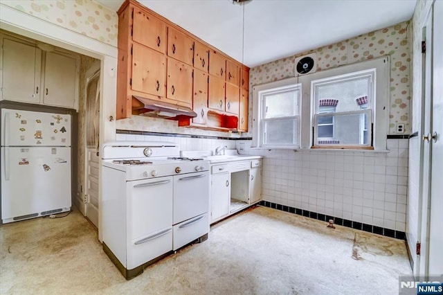kitchen featuring white appliances, under cabinet range hood, light countertops, a sink, and wallpapered walls