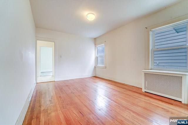 spare room featuring radiator, hardwood / wood-style floors, and baseboards
