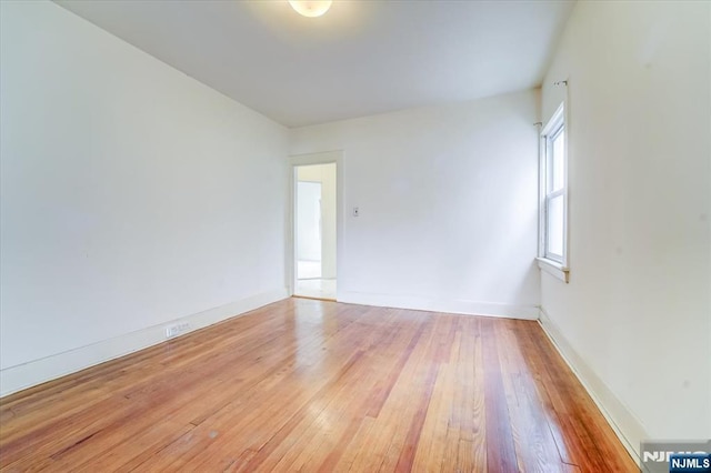spare room featuring light wood-type flooring and baseboards
