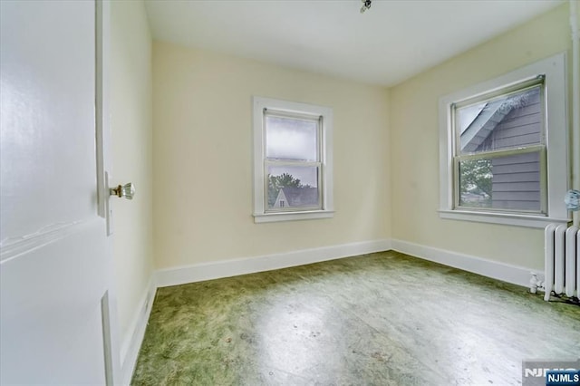 empty room with radiator heating unit and baseboards