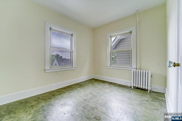 spare room featuring radiator, unfinished concrete flooring, and baseboards