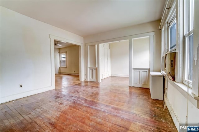 spare room featuring light wood-style floors, a ceiling fan, and baseboards
