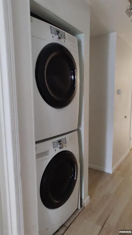 700 Schuyler Unit D16, Kearny, NJ 07032 - washroom with stacked washer and clothes dryer, light wood finished floors, and baseboards