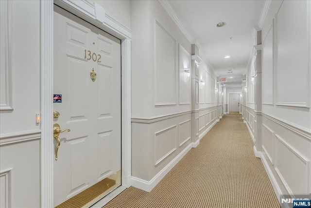 corridor featuring a decorative wall, recessed lighting, and ornamental molding