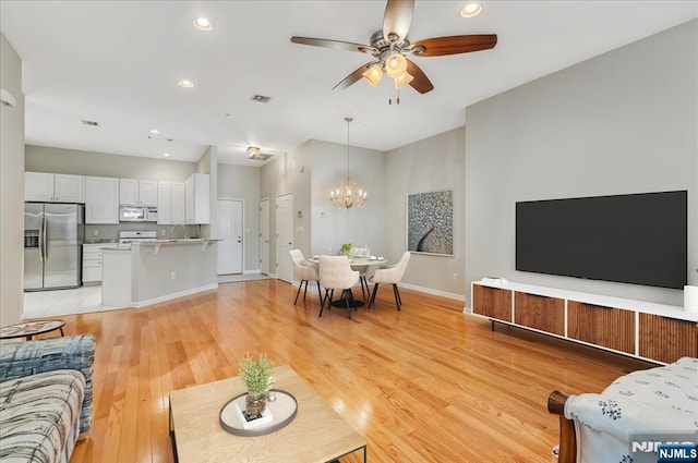 living area featuring a chandelier, ceiling fan, light wood finished floors, recessed lighting, and baseboards