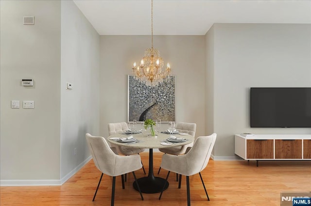 dining area featuring baseboards, a chandelier, and light wood-type flooring