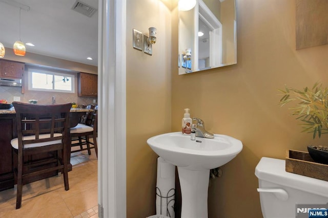 half bathroom featuring decorative backsplash, tile patterned floors, toilet, and recessed lighting