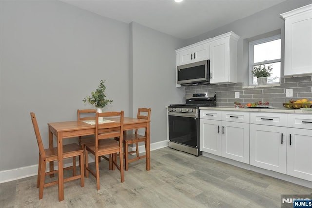 228 Ridgefield Ave, Bogota, NJ 07603 - kitchen with stainless steel appliances, light wood-type flooring, light countertops, tasteful backsplash, and white cabinets