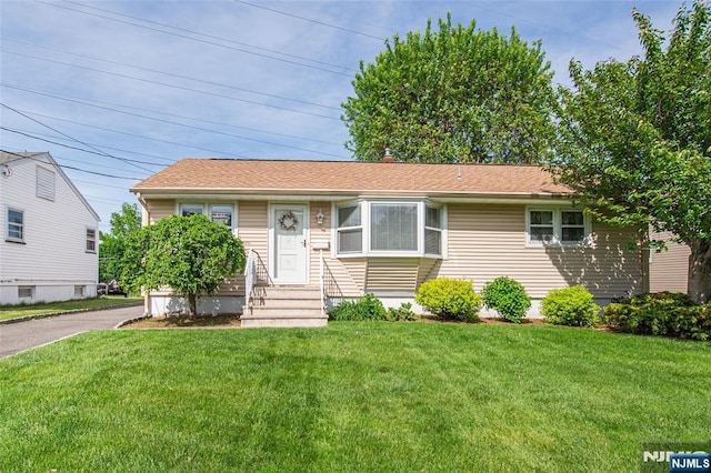 view of front of property with a front yard, entry steps, and roof with shingles