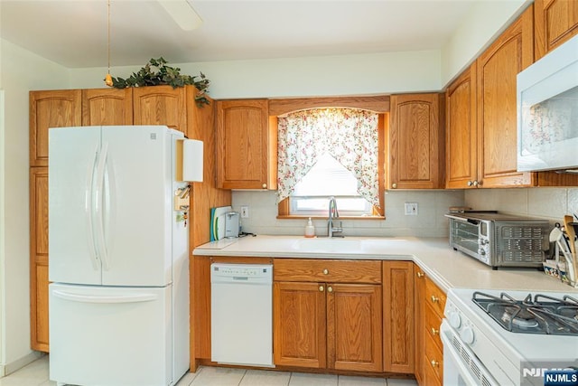 kitchen with white appliances, light countertops, tasteful backsplash, and brown cabinets