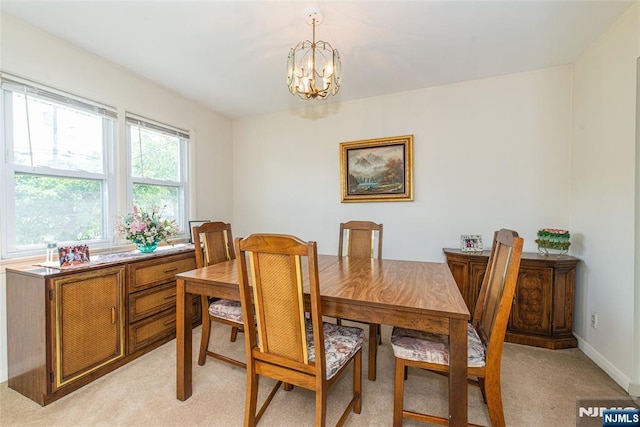 dining space with a chandelier, light carpet, and baseboards