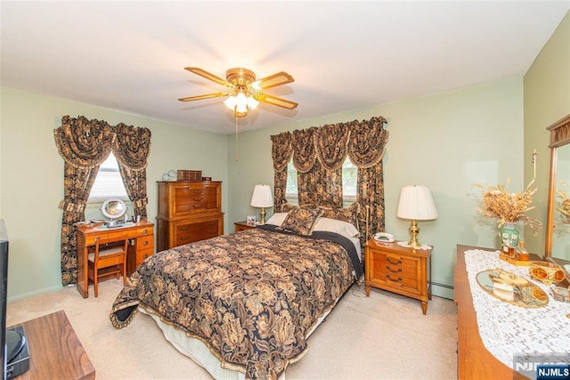 bedroom featuring light colored carpet, a baseboard heating unit, and ceiling fan