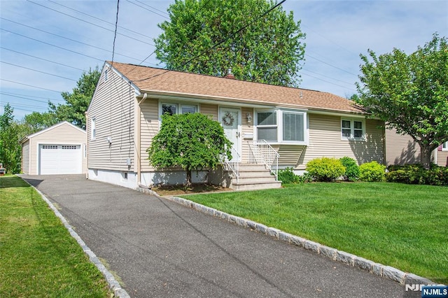 view of front of property featuring an outdoor structure, driveway, a detached garage, and a front yard