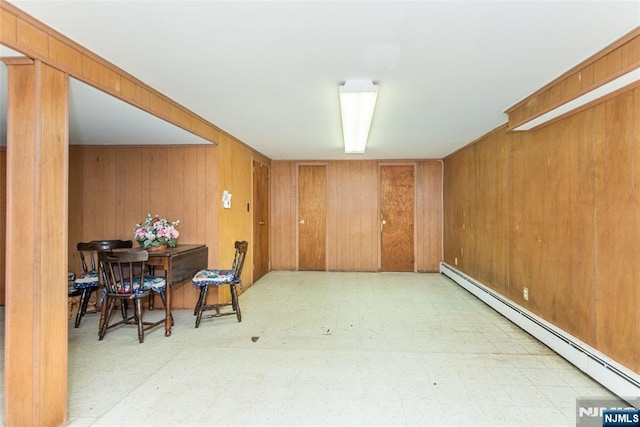 basement featuring baseboard heating, tile patterned floors, and wood walls