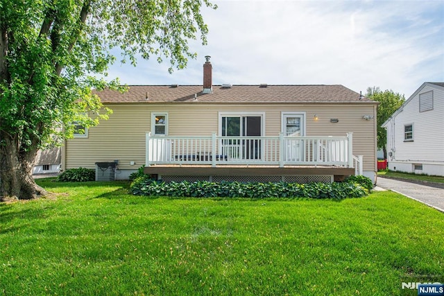 back of property featuring a deck, a chimney, and a yard