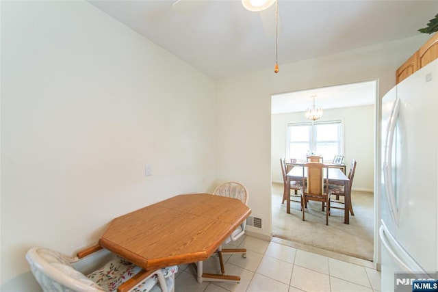 dining space featuring a chandelier, light tile patterned flooring, light carpet, and a ceiling fan